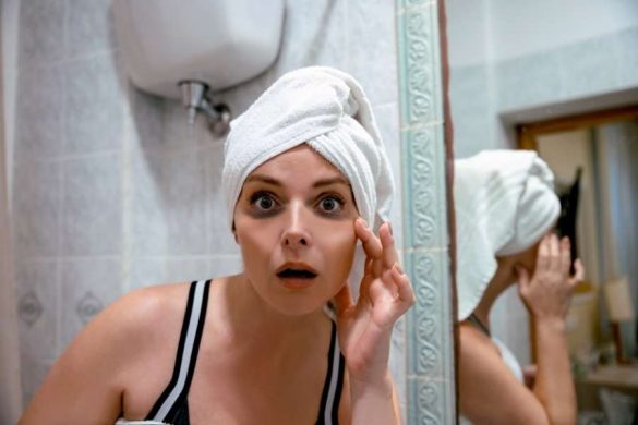 Femme surprise touchant son contour des yeux marqué par des cernes et poches sous les yeux