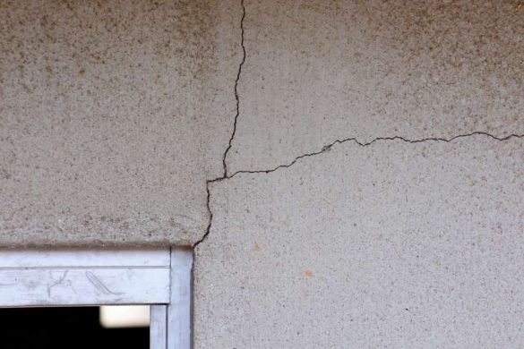 Gros plan sur plusieurs fissures profondes en étoile sur une surface en béton gris, illustrant la nécessité de réparer une fissure dès les premiers signes de détérioration.