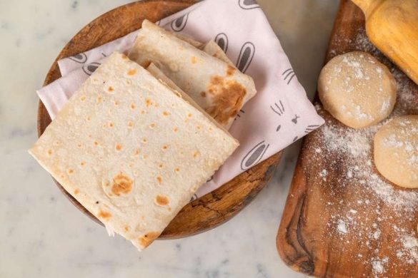 Un pain plat traditionnel présenté sur une planche en bois, symbole de découvertes lors de destinations culinaires.